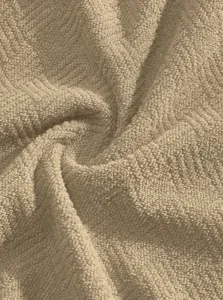 Gedetailleerde close-up van zachte badstof badmantel stof met comfortabele textuur in beige kleur.