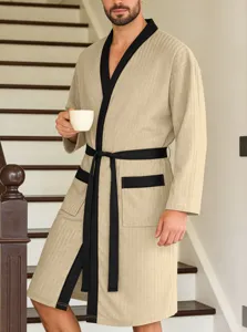 Detail van een comfortabele beige geribbelde badjas met zwarte bies en bijpassende ceintuur.