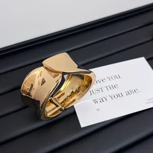 Detailed view of wide open gold fashion metal bangle bracelet, glossy electroplated finish.