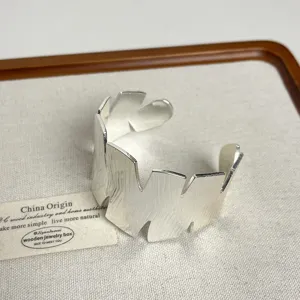 Wide open metal cuff bracelet with irregular jagged edge design, glossy silver finish jewelry.