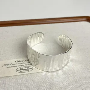 Wide open cuff bracelet detail view, textured silver metallic finish minimalist design jewelry.