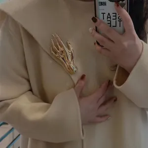Detailaufnahme der goldenen Metallhand Brosche, stylischer Revers-Pin für Anzüge und Schals.