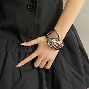 Close-up detail shot of a stylish silver liquid metal hollow cuff bracelet worn on wrist.