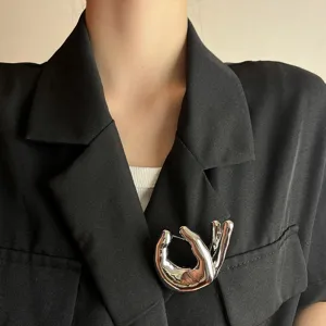 Close-up detail of a stylish metal OK hand gesture brooch, chic lapel pin accessory.