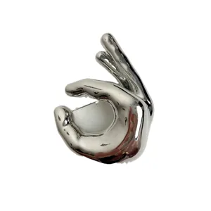 Close-up detail of a sleek silver metal OK hand gesture brooch, highly polished and stylish accessory.