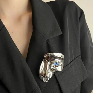Surrealistische zilveren metalen gezicht broche met blauw oog en neusring vintage sieraden.