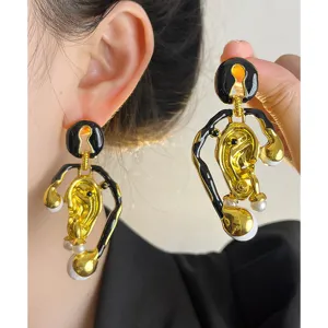 Boucles d'oreilles asymétriques dorées et noires style surréaliste vintage avec perles.
