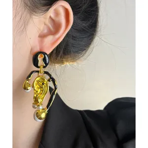 Boucles d'oreilles dorées surréalistes vintage au design artistique asymétrique avec perle.