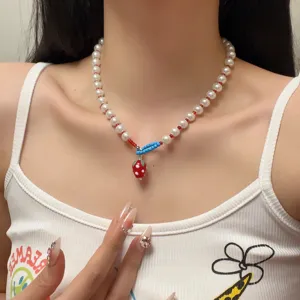 Detailopname van de schattige aardbei hanger en parels choker halsketting gedragen.