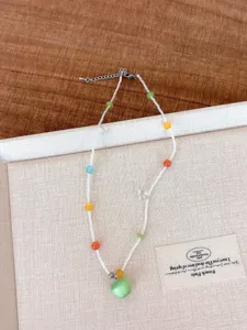 Gedetailleerd overzicht van de dopamine gekleurde kralenketting met groene appelhang.