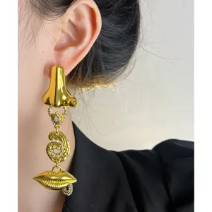 Boucles d'oreilles asymétriques dorées style surréaliste vintage avec nez et lèvres.