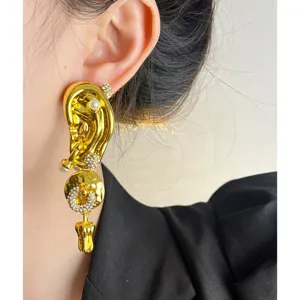 Boucles d'oreilles pendantes forme d'oreille dorees avec perles et strass gros plan