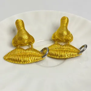 Boucles d'oreilles nez et lèvres dorées surréalistes, bijoux tendance uniques.