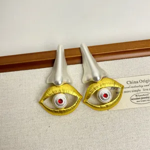 Gros plan détaillé de boucles d'oreilles asymétriques surréalistes au design facial unique.