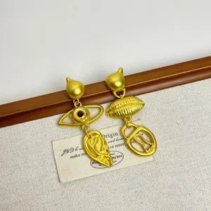 Boucles d'oreilles asymétriques dorées surréalistes avec des motifs uniques d'yeux et de lèvres.