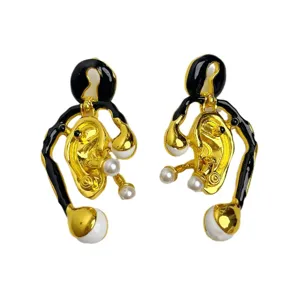 Boucles d'oreilles asymétriques dorées style vintage avec perle et émail noir design.