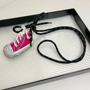 Detalle de collar con colgante de zapatilla lona strass rosa, charm sneaker largo.