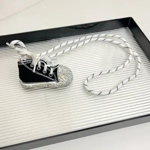 Gran detalle de collar con colgante de zapato de lona de diamantes con cuerda larga.