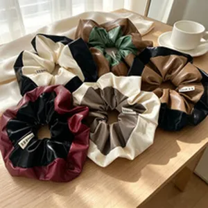 Collection of assorted two-tone PU leather scrunchies arranged on a minimalist table