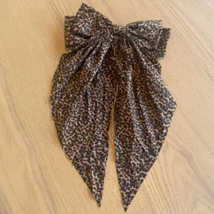 Nahaufnahme einer Vintage-Haarklammer mit Leopardenmuster-Schleife und langen Bändern.
