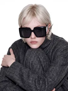 Stylish close-up of oversized square black sunglasses paired with silver gothic ear cuff