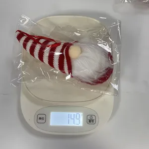 Vue détaillée d'un gnome de Noël rayé pesé sur une balance, affichant 14,9 g.