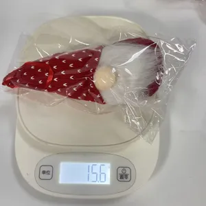 Mesure détaillée du poids d'un gnome de Noël tricoté rouge sur une balance numérique