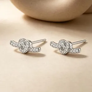Detailed macro shot of silver heart knot stud earrings with shimmering zircon pavé