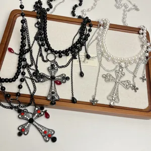 Vue détaillée de chaînes multicouches avec perles et pendentifs croix en strass scintillants.