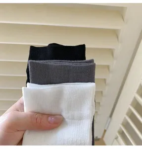 Close-up detail shot of ribbed high tube socks shown in classic black, grey, and white colors.