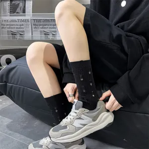 Close-up detail of women's black distressed slouch socks worn with trendy sneakers in studio.