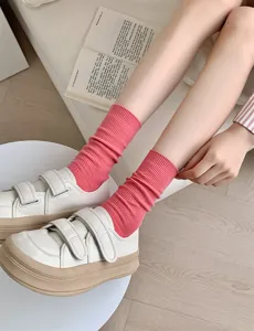 Detailed shot of women's solid color candy pink ribbed mid-tube cotton socks paired with shoes.