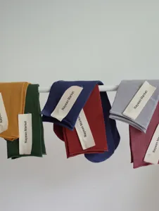 Detail shot of rolled-edge cotton mid-tube socks in vibrant candy colors hanging on a white bar.