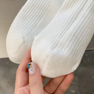 Vue de détail de chaussettes en tricot côtelé blanc montrant texture douce et rayures.