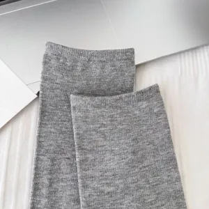 Primo piano di calzini a tubo in maglia grigia con texture morbida e polsini a coste fini.