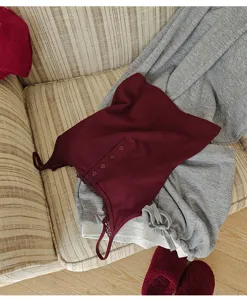 Detailed view of women ribbed wine red camisole with lace trim and grey lounge pants.