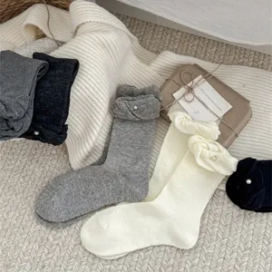 Primo piano dettaglio calzini donna perlati con bordo a sbuffo, flatlay accogliente.