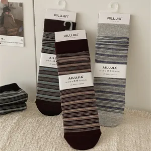 Detailed shot of striped mid-calf socks with packaging tags, cozy cotton texture and soft feel.