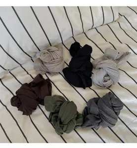 Close-up detail of multi-color ribbed tights bundles arranged neatly on striped bedding.