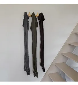 Detailed view of high-density wool blend cable-knit tights hanging on wall hook display.