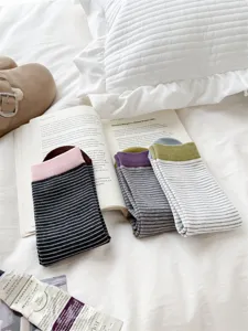 Detailed shot of Japanese style striped mid-tube cotton women's socks displayed neatly on cozy bed.