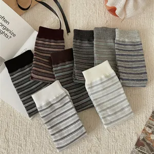 Close-up detail of cozy striped mid-calf socks in various neutral tones, laid out neatly.