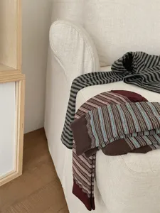 Close-up detail of cozy striped mid-tube socks on a soft sofa, autumn daily fashion texture view.