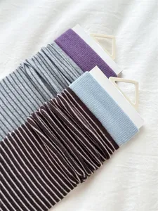 Close-up detail of Japanese style striped slouch socks with ribbed cuffs and hanging cards.