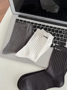 Detailaufnahme von einfarbigen gerippten Freizeitsocken in Grau, Weiß und Dunkelgrau.