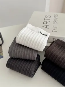 Detailansicht breitgerippter Baumwoll-Herrensocken in mehreren Farben mit Buch-Requisite.