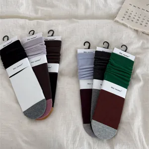 Color-blocked mid-calf slouch socks with cardboard hangers, cozy cotton fabric stylish.