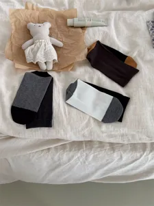Detailed view of cozy contrast color crew socks styled with cute plush toy on cozy bed.