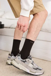 Nahaufnahme von einfarbigen gerippten Herrensocken in mittlerer Schafthöhe mit trendigen Sneakers.