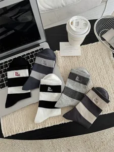 Detailansicht lässiger Herrensocken mit breiten Streifen und feiner Buchstabenstickerei.